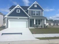 Charming two-story home with gray siding, a two-car garage, and a well-manicured lawn under a blue sky at 1111 Forest Bend Dr., Calabash, NC 28467
