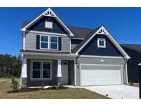 Beautiful two-story home with a two car garage and gray siding against a blue sky at 1111 Forest Bend Dr., Calabash, NC 28467