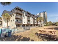 Coastal condo building with multi-level balconies, pool and picnic tables, offering a relaxing outdoor space at 201 N 76Th Ave. N # B-2, Myrtle Beach, SC 29572