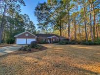 Charming brick home featuring an attached two-car garage, lush landscaping, and mature trees at 270 Georgetown Dr., Pawleys Island, SC 29585