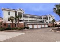 Low angle view of condo building with garages below and palm trees flanking the right side at 4827 Orchid Way # 201, Myrtle Beach, SC 29577