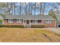 Charming brick home featuring a covered front porch and mature landscaping at 504 Danner Dr., Conway, SC 29526