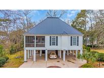 Charming elevated home featuring a metal roof, screened porch, and stilt construction at 830 Channel Cat Cove, Murrells Inlet, SC 29576