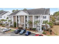 Three-story condo building showcasing brick facade, white columns, and exterior staircases with mature palm trees at 100 Birch N Coppice Dr. # 12, Surfside Beach, SC 29575