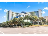 Stunning exterior view of a resort-style building with lush landscaping and palm trees against a clear blue sky at 1105 S Ocean Blvd. # 1134, Myrtle Beach, SC 29577