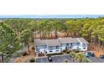 Inviting two-story condo with a blue exterior, surrounded by lush trees and well-maintained landscaping at 1849 Crooked Pine Dr. # C-5, Surfside Beach, SC 29575