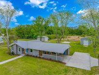 An exterior aerial view of a charming gray brick home with a large green yard and metal roof at 2360 Highway 701 North, Loris, SC 29569