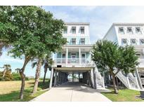 Beautiful raised beach house with blue siding, white trim, and a covered porch near green foliage at 1411-A N Ocean Blvd., Surfside Beach, SC 29575