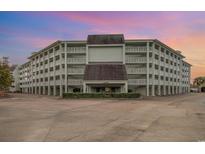 Multi-level condo building featuring balconies, manicured shrubbery, and spacious parking at 14290 Ocean Hwy. # 101, Pawleys Island, SC 29585