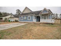 Charming blue home featuring a inviting front porch and well-maintained lawn at 1741 Rice St., Georgetown, SC 29440