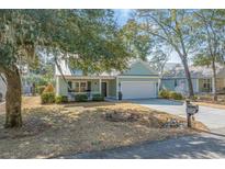 Charming home with a well-manicured front yard, a white picket fence, and an attached two-car garage at 182 Minnow Dr., Pawleys Island, SC 29585