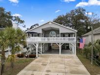 Coastal home featuring a spacious porch, an American flag, and covered parking at 300 Oak Lake Circle, North Myrtle Beach, SC 29582