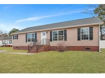 Charming single-story home featuring a classic tan exterior and a well-manicured front yard at 308 Stone Throw Dr., Murrells Inlet, SC 29576