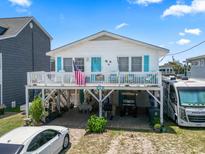 Charming raised beach house with white siding, an American flag, and a spacious front deck at 315 60Th Ave. N, North Myrtle Beach, SC 29582