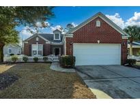 Charming brick home with a well-manicured lawn, white picket fence, and attached two-car garage at 3507 Club Course Dr., North Myrtle Beach, SC 29582