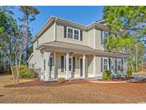 Inviting two-story home featuring a metal roof, black shutters and a charming front porch with white columns at 425 Retriever Ct., Murrells Inlet, SC 29576