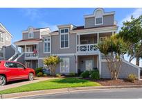 Charming condo featuring two stories, gray wood shingles, and a well-maintained lawn with shrubs and trees at 4396 Baldwin Ave. # 19, Little River, SC 29566