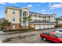 Bright yellow condo building features private balconies, garages, and well-maintained landscaping at 4872 Dahlia Ct. # 202, Myrtle Beach, SC 29577