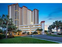 Coastal high-rise condo building featuring a parking garage and lush tropical landscaping at 8500 Margate Circle # 1604, Myrtle Beach, SC 29572