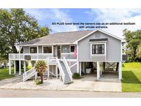 Charming gray beach house on stilts with white railings and a welcoming staircase entrance at 202 Old Harbour Ct., Little River, SC 29566