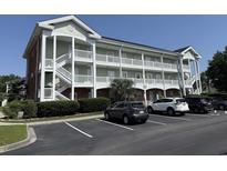 Exterior view of a three-story condominium building with white balconies and well-maintained landscaping at 3955 Gladiola Ct. # 301, Myrtle Beach, SC 29588