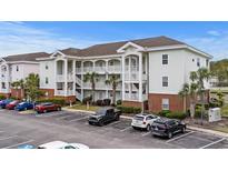 Three-story condo with a parking lot and palm trees at 4140 Hibiscus Dr. # 303, Little River, SC 29566