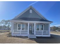 Charming, light blue, single-story home featuring a welcoming front porch and beautiful architectural details at 8125 Living Tide Dr., Myrtle Beach, SC 29572