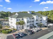 Three-story white condominium building with green shutters and well-maintained landscaping and parking lot at 131 Greenside Villas Dr. # B10, Little River, SC 29566