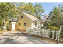 Charming yellow home with a white picket fence and a lush, tree-filled yard at 2120 Adams Way, Little River, SC 29566