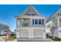 Charming two-story home with gray siding, white trim, and a two-car garage offers timeless curb appeal at 223 Gloucester Way, Little River, SC 29566