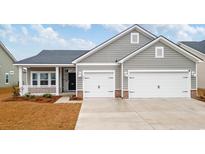 Charming gray home featuring a two-car garage, covered porch, and well-maintained landscaping at 3011 Visionary Dr., Myrtle Beach, SC 29588