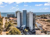 An exterior view of an oceanfront condo building on a sunny day with blue skies and landscaping at 311 69Th Ave. N # 404, Myrtle Beach, SC 29572