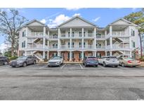 Attractive condo building with white facade, multiple balconies, and well-maintained parking area at 4449 Turtle Ln. # 3-C, Little River, SC 29566