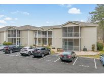 Low-angle view of condos with tan siding, screened porches, and ample parking on a partly cloudy day at 4502 Sweetwater Blvd. # 4502, Murrells Inlet, SC 29576