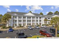 Exterior view of three story condo complex with ample parking spaces and manicured greenery at 5060 Windsor Green Way # 304, Myrtle Beach, SC 29579