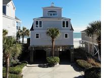 Beach house on stilts with a view of the ocean and palm trees, featuring a ground-level covered parking area at 547 South Waccamaw Dr., Garden City Beach, SC 29576