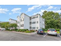 Three story condo featuring well-manicured landscaping, ample parking, and a clean white exterior at 1529 Lanterns Rest Dr. # 201, Myrtle Beach, SC 29579