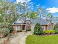 Charming brick home featuring a well-manicured lawn, mature trees, and an inviting front entrance at 25 Berwick Dr., Pawleys Island, SC 29585