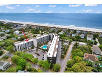 Oceanfront condo complex features a swimming pool and private beach access, surrounded by lush greenery and neighborhood homes at 423 Parker Dr. # 306, Pawleys Island, SC 29585