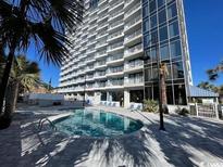 Inviting swimming pool with lounge chairs in front of a modern condo building, perfect for relaxation and enjoyment at 5511 N Ocean Blvd. # 1006, Myrtle Beach, SC 29577