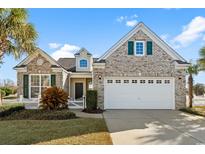 Charming brick home with a two-car garage and a well-manicured lawn featuring a white picket fence at 5719 Whistling Duck Dr., North Myrtle Beach, SC 29582