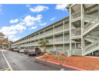 Coastal condo building with covered balconies, a stairway, and ample parking space at 5905 South Kings Hwy. # 5308, Myrtle Beach, SC 29575