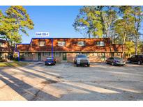Brick townhome featuring a multi-car parking area, wood-shingled roofing, and mature landscaping at 1025 Carolina Rd. # Ee-1, Conway, SC 29526