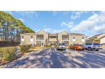 Inviting two-story apartment building with tan siding, screened porches, and ample parking at 1915 Bent Grass Dr. # E, Surfside Beach, SC 29575