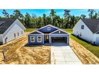 Charming one-story home with a blue exterior, open garage, and concrete driveway at 327 Dunlin Pl, Conway, SC 29526