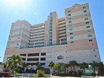 Low-angle view of Crescent Keyes resort, a tall tan-colored building in Myrtle Beach at 1903 S Ocean Blvd. # 701, North Myrtle Beach, SC 29582