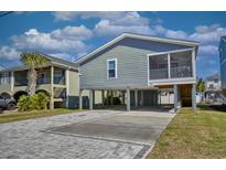 Coastal home on stilts featuring a paved driveway and screened-in porch for outdoor relaxation at 308 24Th Ave. N, North Myrtle Beach, SC 29582