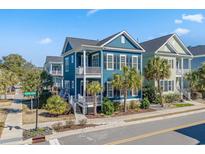 Charming two-story blue home featuring a double porch, palm trees, and lovely landscaping at 7624 Azure Dr., Myrtle Beach, SC 29572