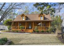 Charming log cabin featuring a cozy front porch, dormer windows and mature landscaping at 1303 Elizabeth St., North Myrtle Beach, SC 29582