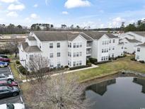 View of an attractive three-story condo building and surrounding parking area and pond at 2276 Essex Dr. # H, Surfside Beach, SC 29575